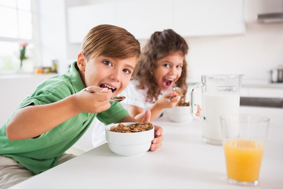 Um casal de crianças faz um lanche com cereais sem açúcar, leite e sucos naturais: uma boa opção - Crédito: wavebreakmedia/Shutterstock
